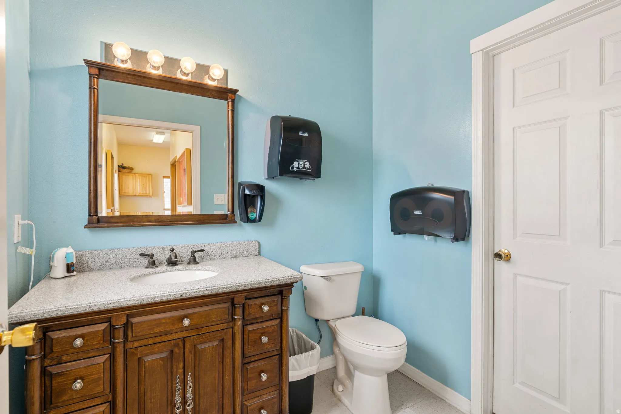 Bathroom vanity with wood-finish cabinetry, a light-toned countertop, and an undermount sink