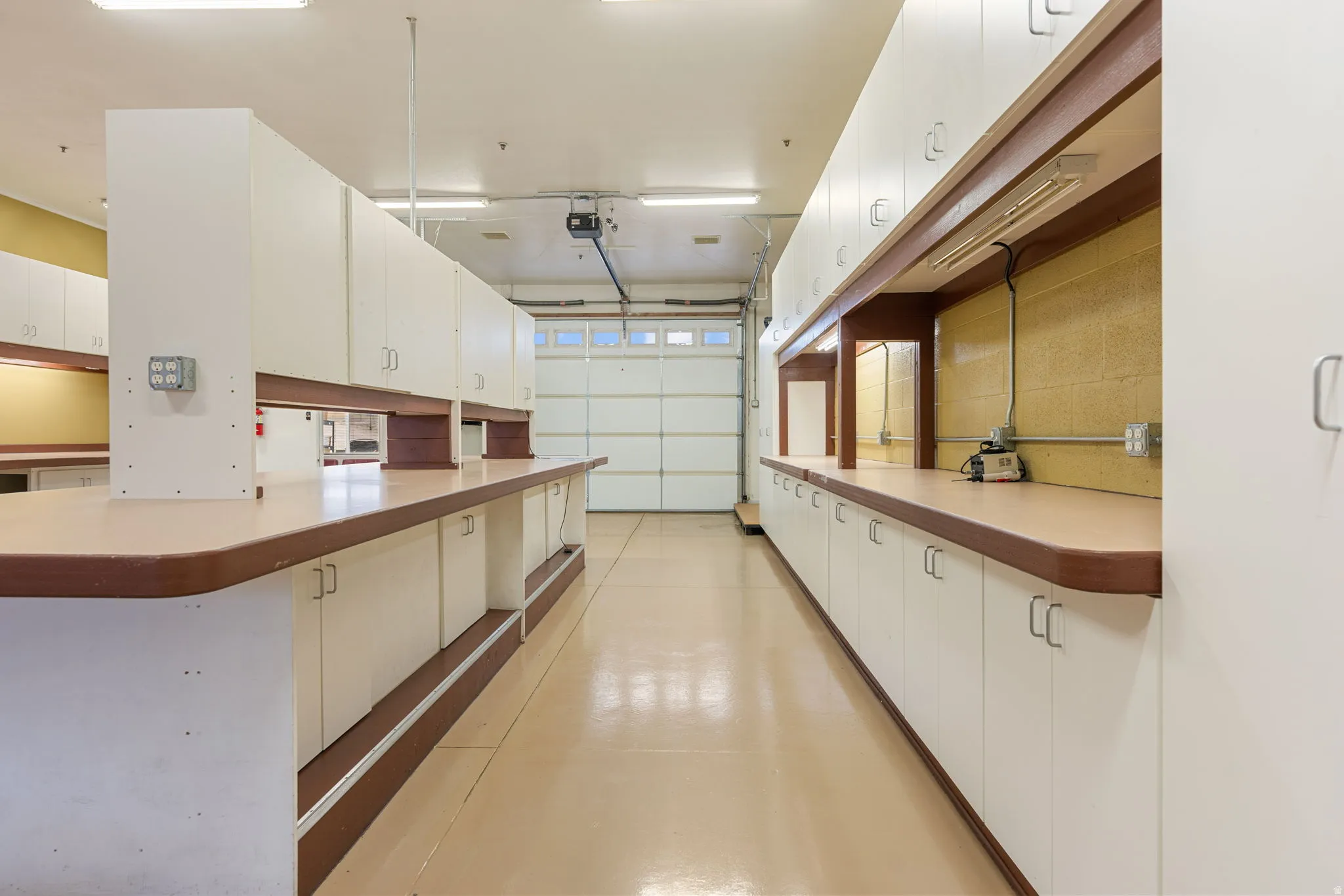 Spacious workspace featuring extensive built-in cabinetry, durable countertops, and overhead fluorescent lighting