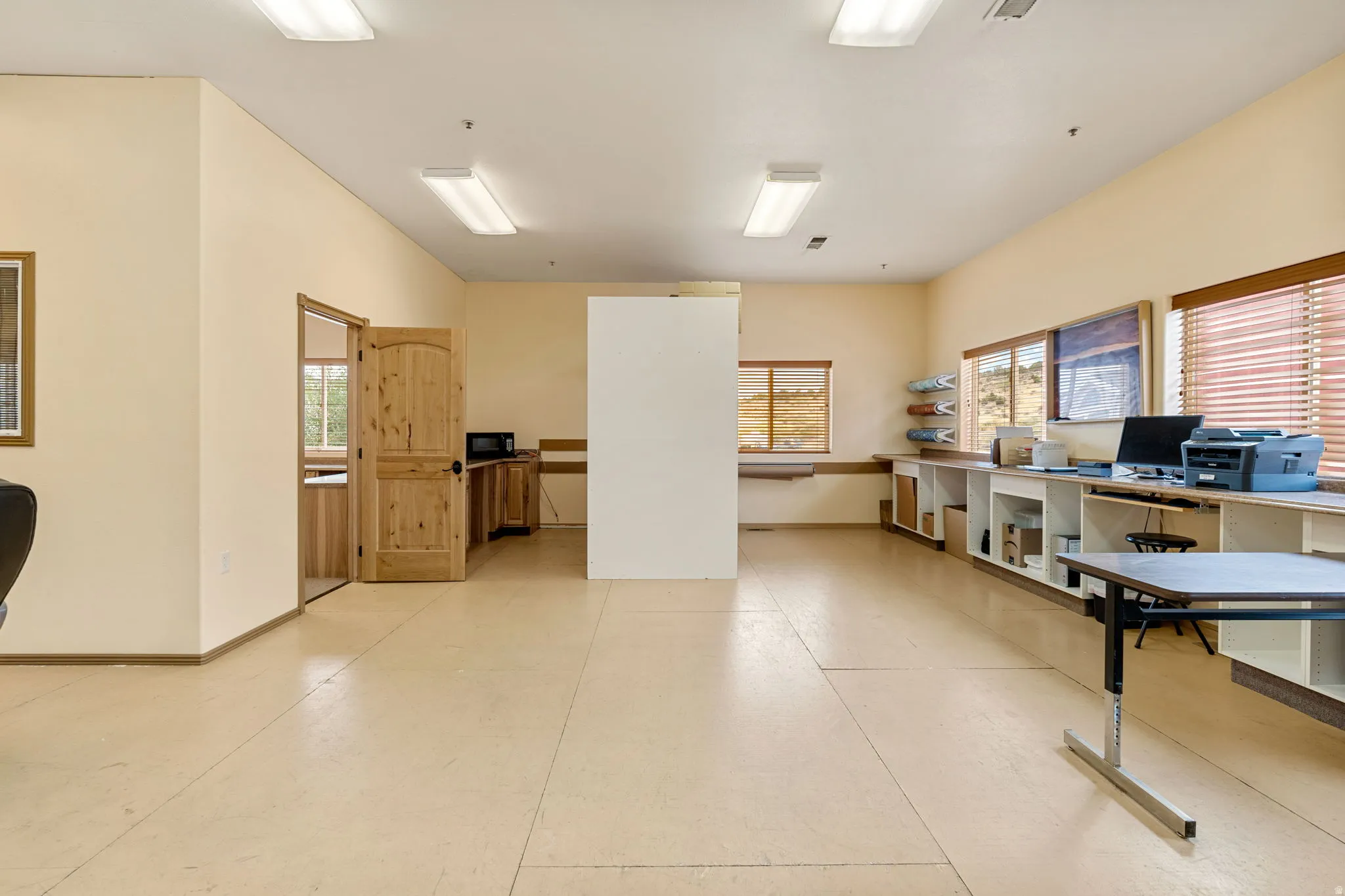 Expansive open room featuring light-toned flooring, recessed lighting, and multiple windows