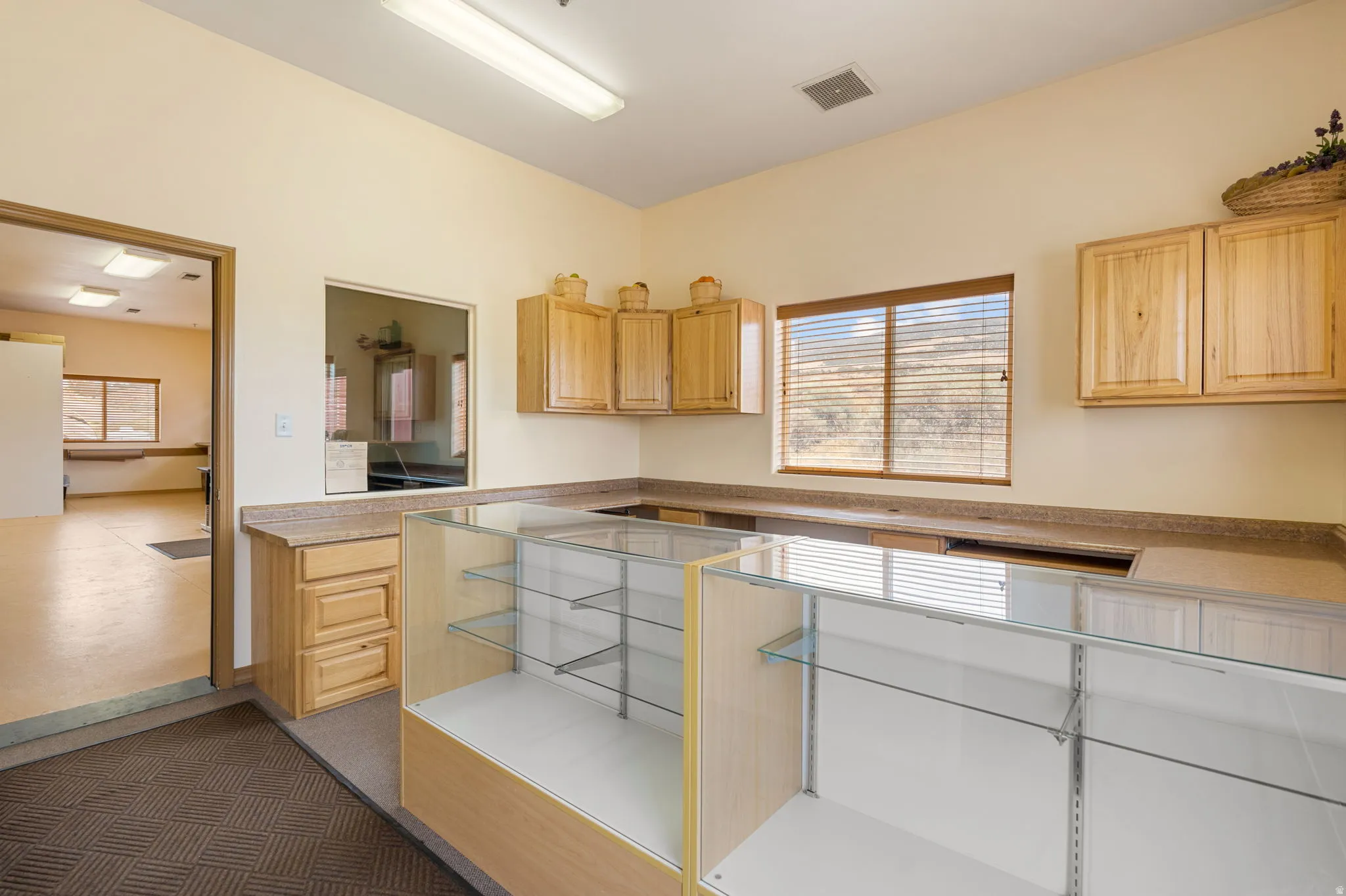 Spacious commercial interior featuring a large service counter with built-in display cases, wood-finish cabinetry, and neutral-toned countertops
