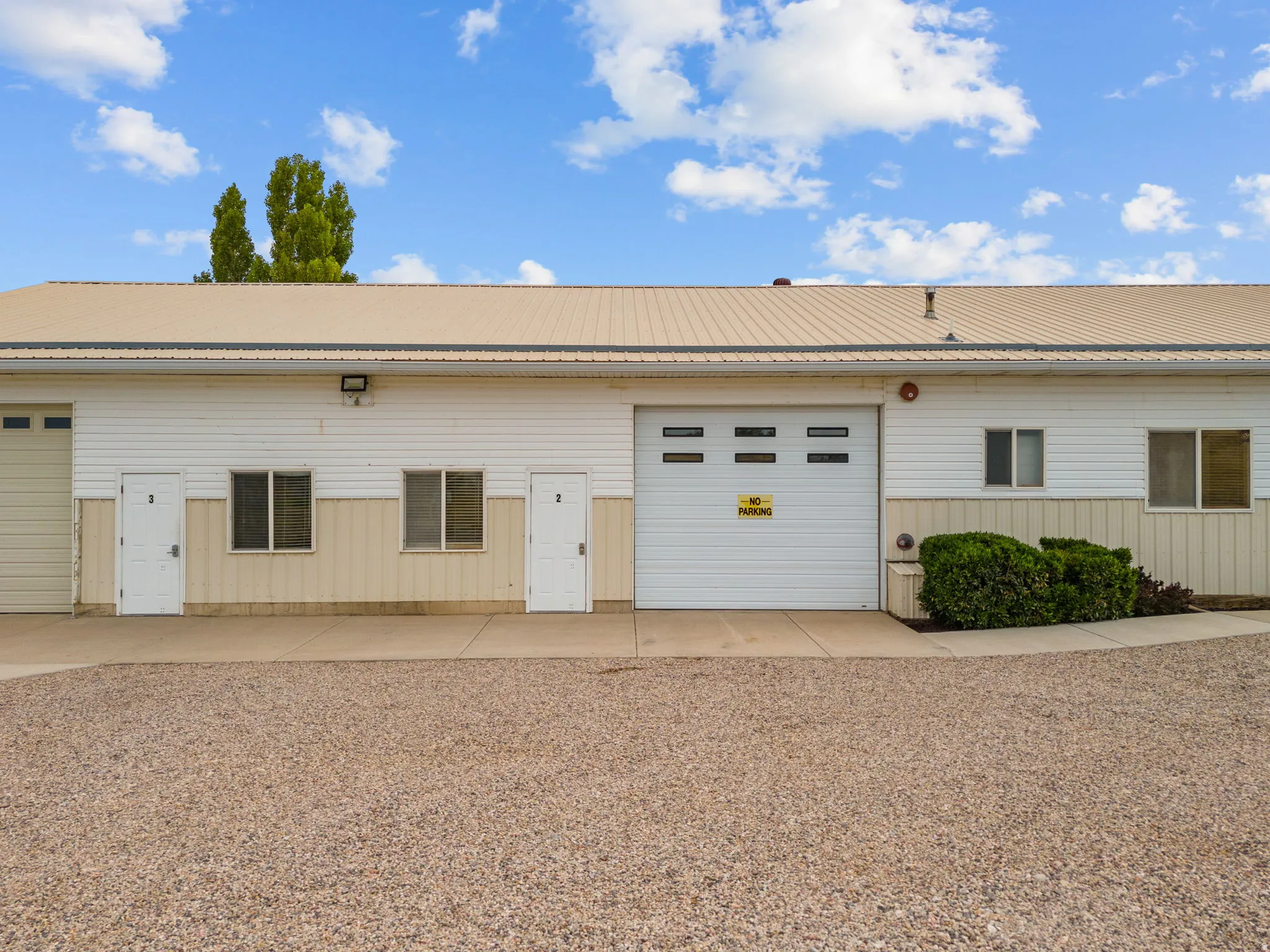 Building exterior featuring a metal roof, multiple entry doors, and a large garage door