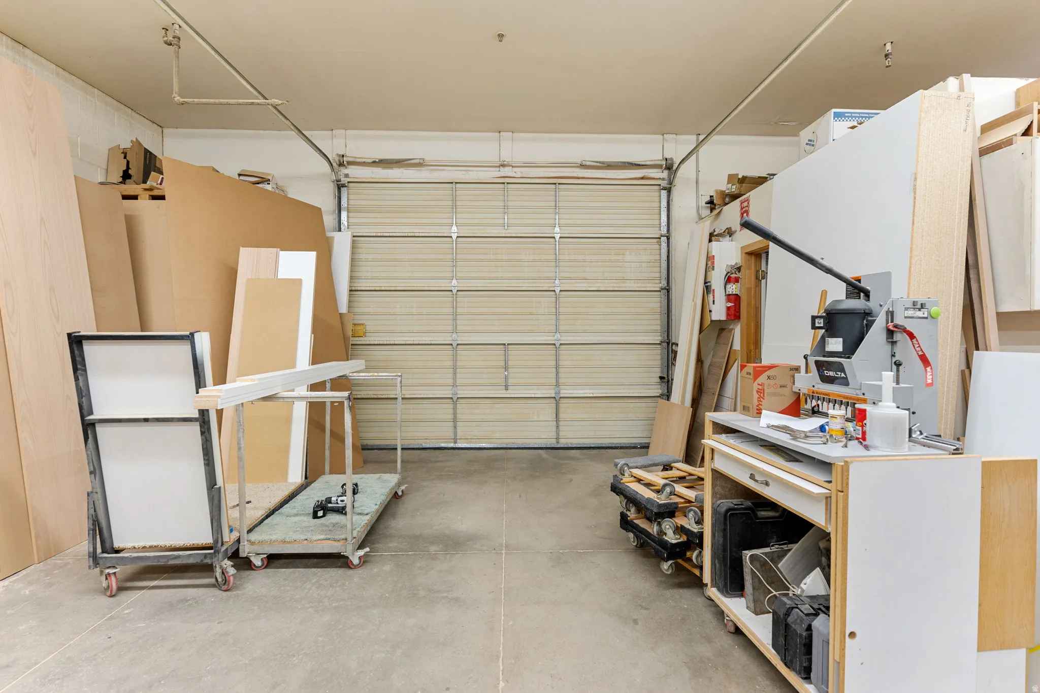 Spacious interior featuring a large overhead door, concrete flooring, and overhead lighting