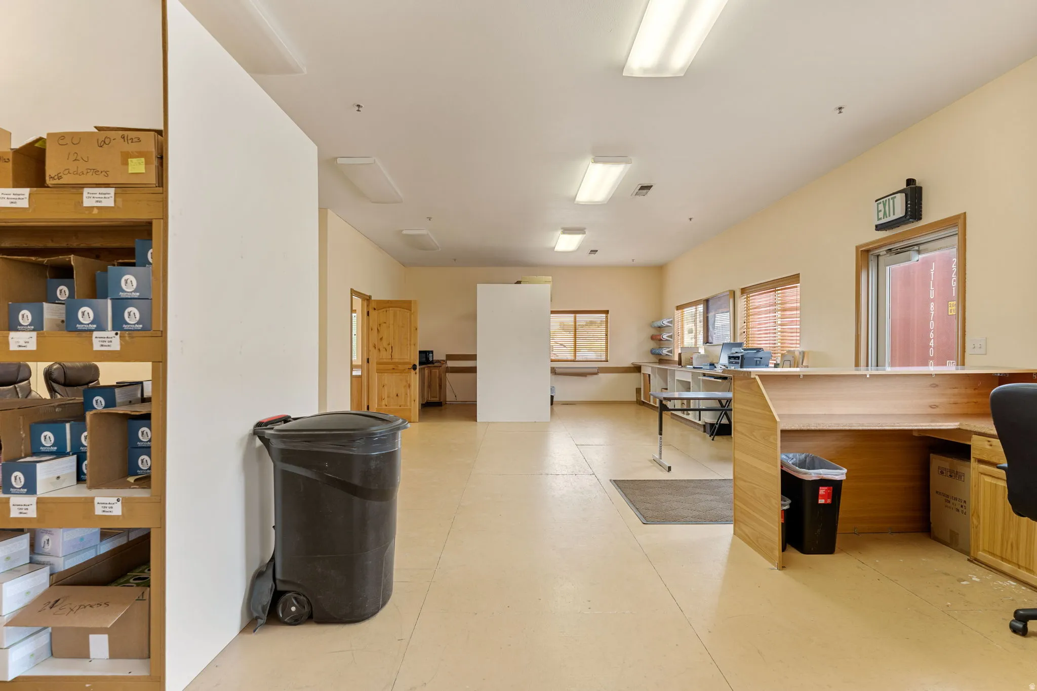 Spacious open-plan interior featuring light-toned flooring, recessed lighting, and a wood-finish reception counter