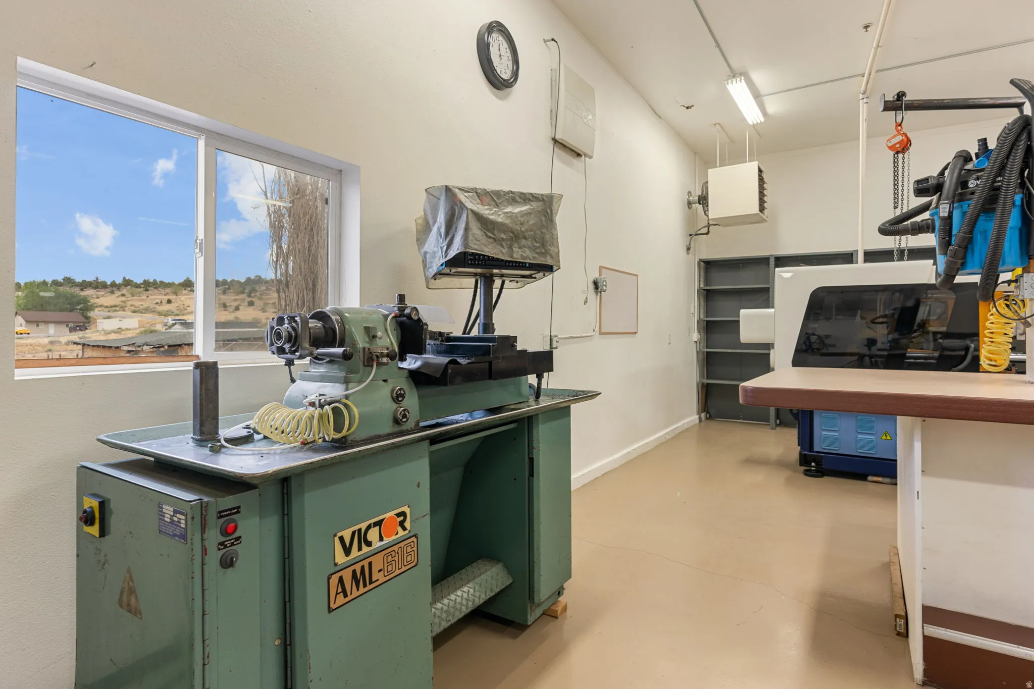 Spacious workroom featuring a large window, light-colored flooring, and built-in shelving