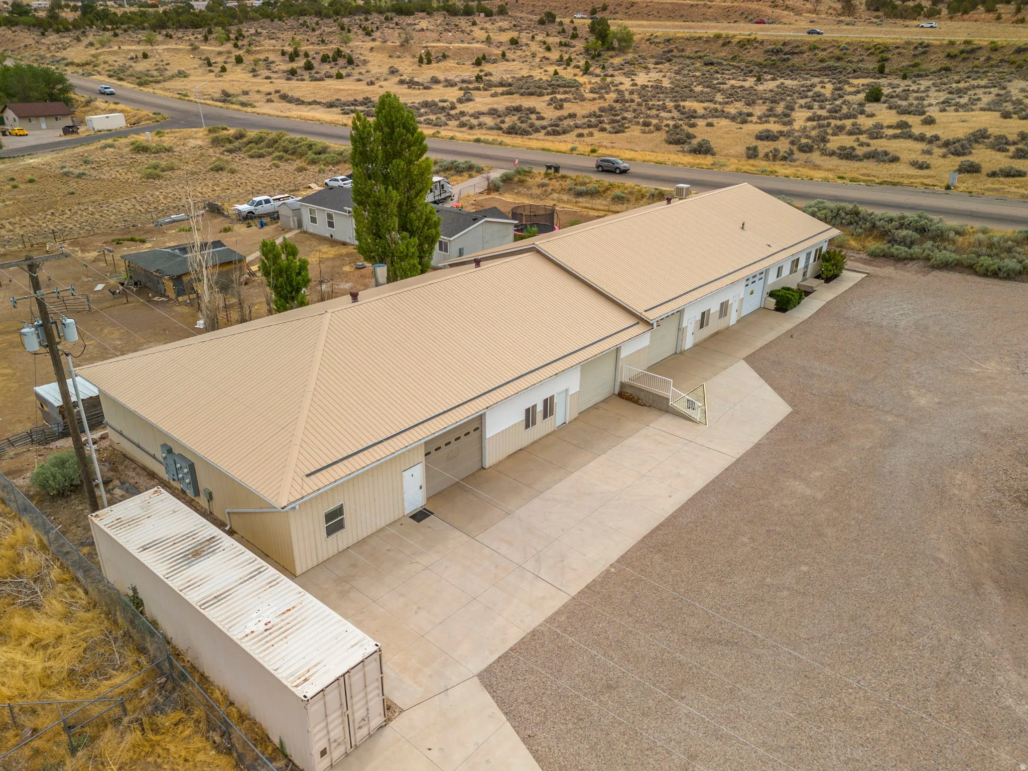 Expansive commercial property featuring a tan metal roof, multiple garage doors, and a concrete driveway