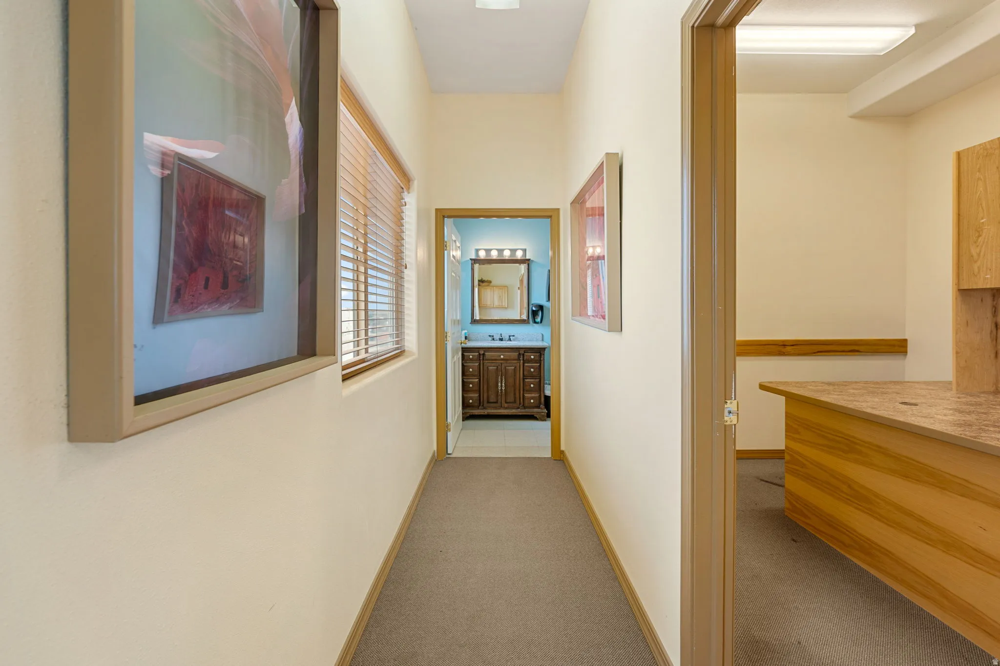 Hallway featuring neutral-toned walls, carpeted flooring, and a window with blinds