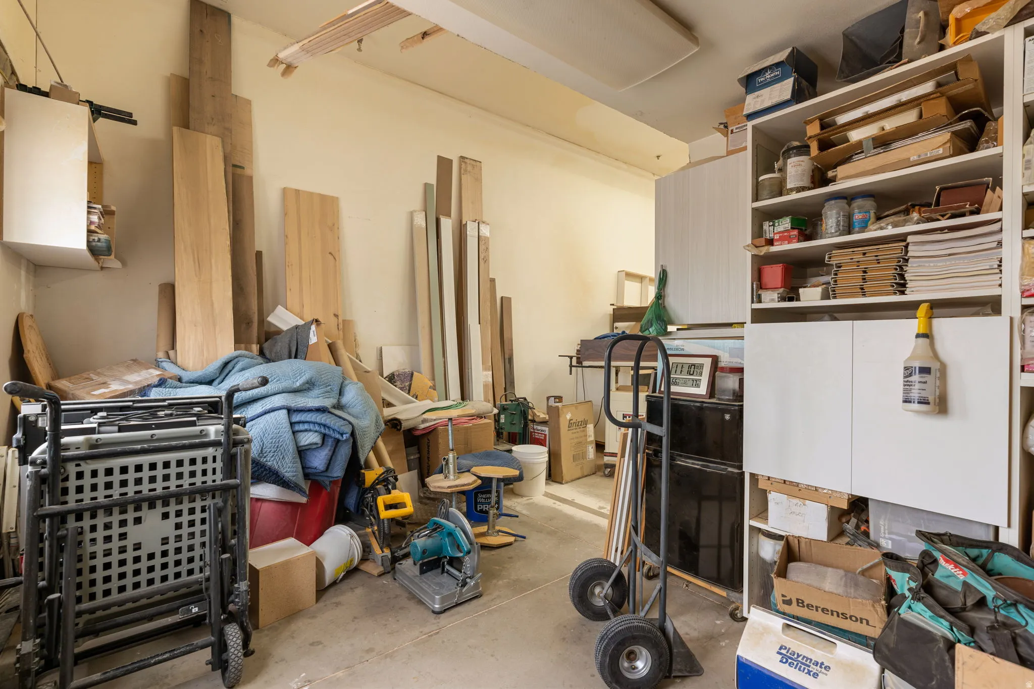 Utility space featuring concrete flooring, built-in shelving, and wall-mounted cabinetry