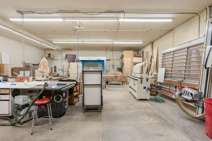 Expansive workshop space with concrete flooring, fluorescent lighting, and extensive built-in work surfaces