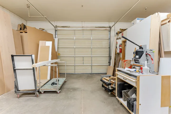 Spacious interior featuring a large overhead door, concrete flooring, and overhead lighting