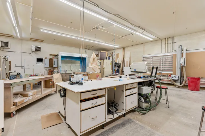Spacious workshop area featuring concrete flooring and ample overhead fluorescent lighting