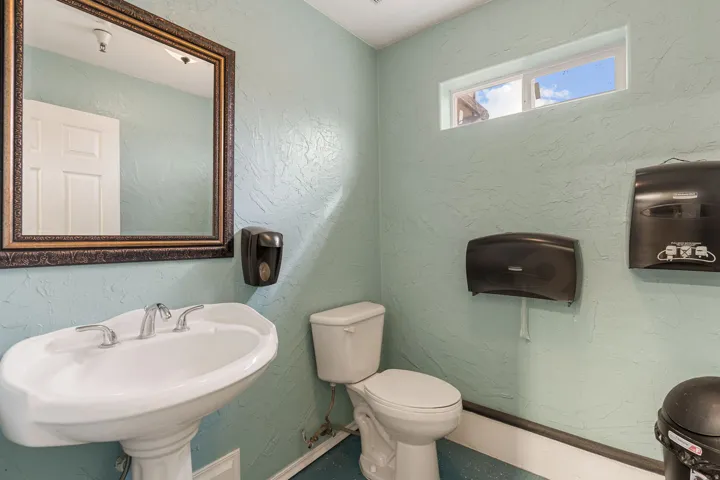 Pedestal sink with chrome fixtures and an ornate framed mirror