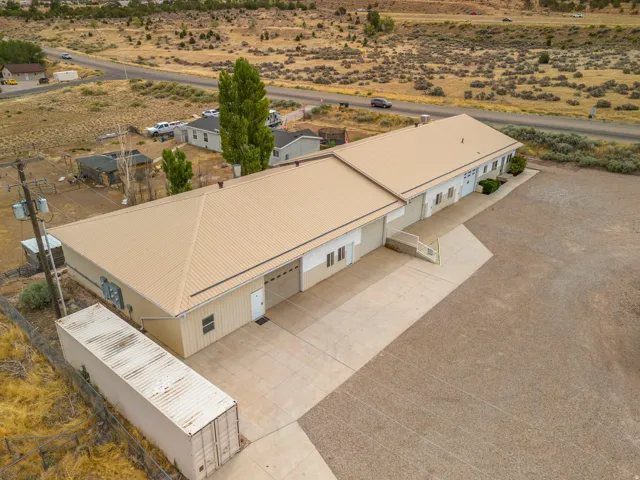 Expansive commercial property featuring a tan metal roof, multiple garage doors, and a concrete driveway