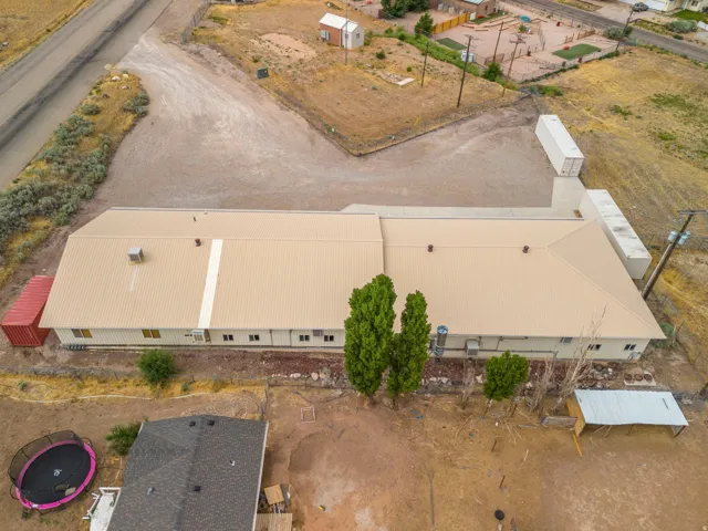 Expansive property featuring a large structure with a tan metal roof and siding, multiple windows, and extensive gravel areas