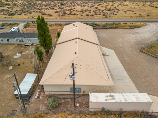 Expansive commercial building featuring a tan metal roof and siding, concrete apron, and gravel parking area
