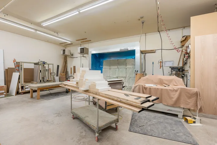 Spacious workshop featuring concrete flooring, fluorescent overhead lighting, and white painted walls