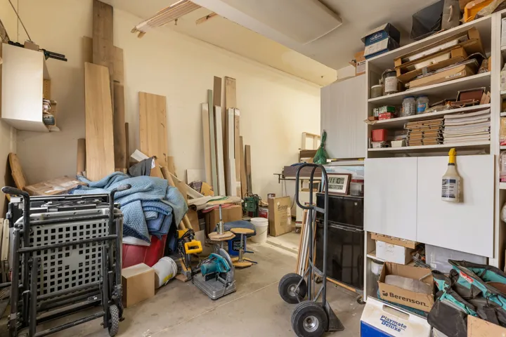 Utility space featuring concrete flooring, built-in shelving, and wall-mounted cabinetry