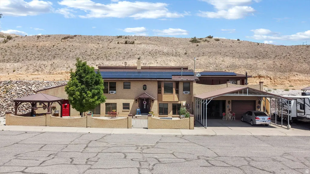Two-story residence featuring a front entry courtyard with a gazebo and brick fencing