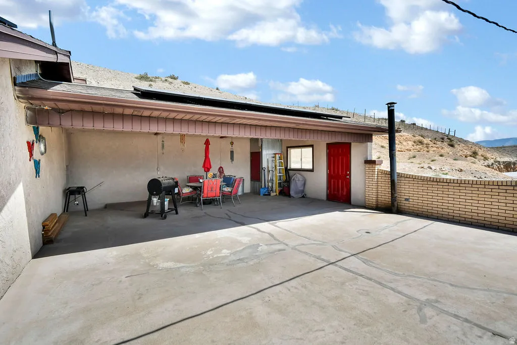 Expansive concrete patio with a covered section, featuring a red entry door and a window