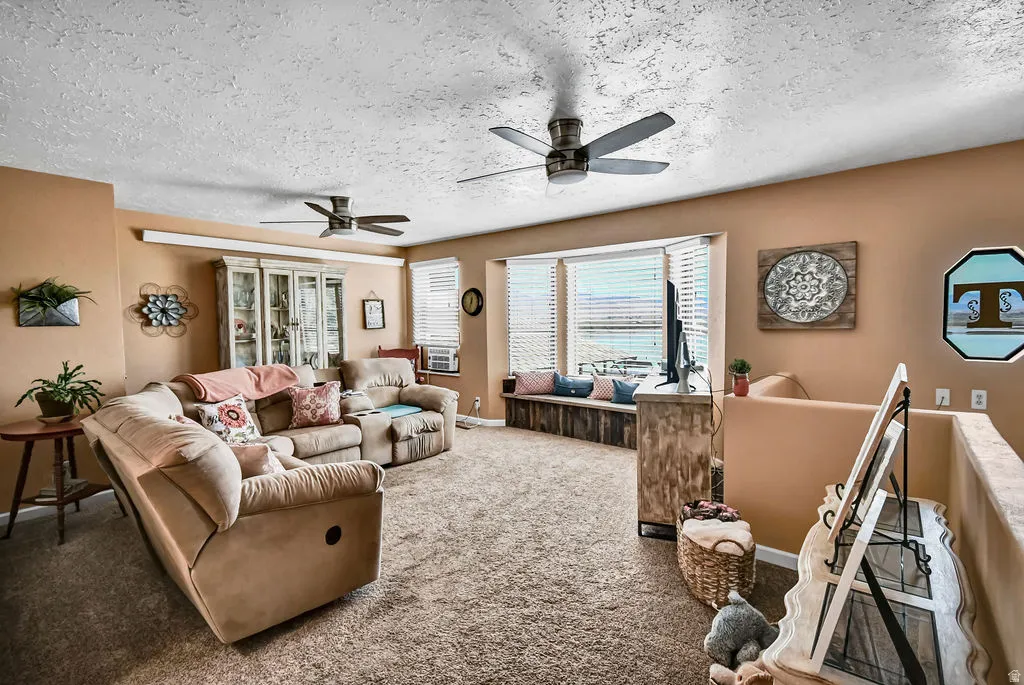 Spacious interior featuring a bay window with integrated seating, two ceiling fans, textured ceilings, and neutral-toned walls