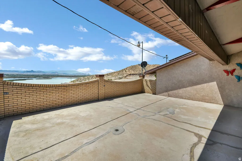 Concrete patio with a curved brick wall, overlooking a body of water and distant mountains