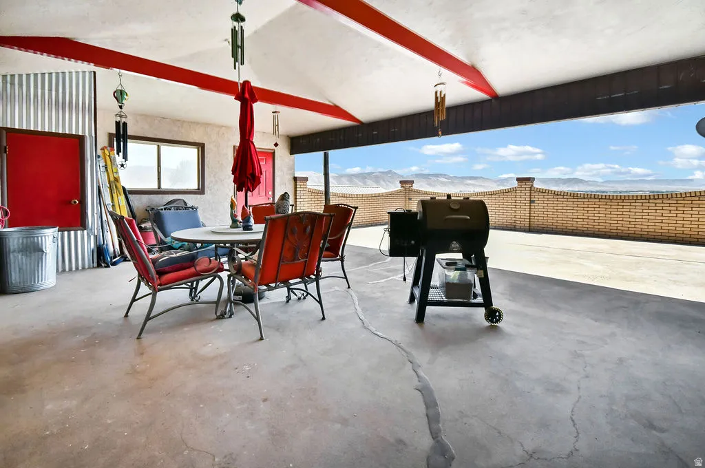 Covered patio with a concrete surface, red-painted structural beams, and a corrugated metal accent wall