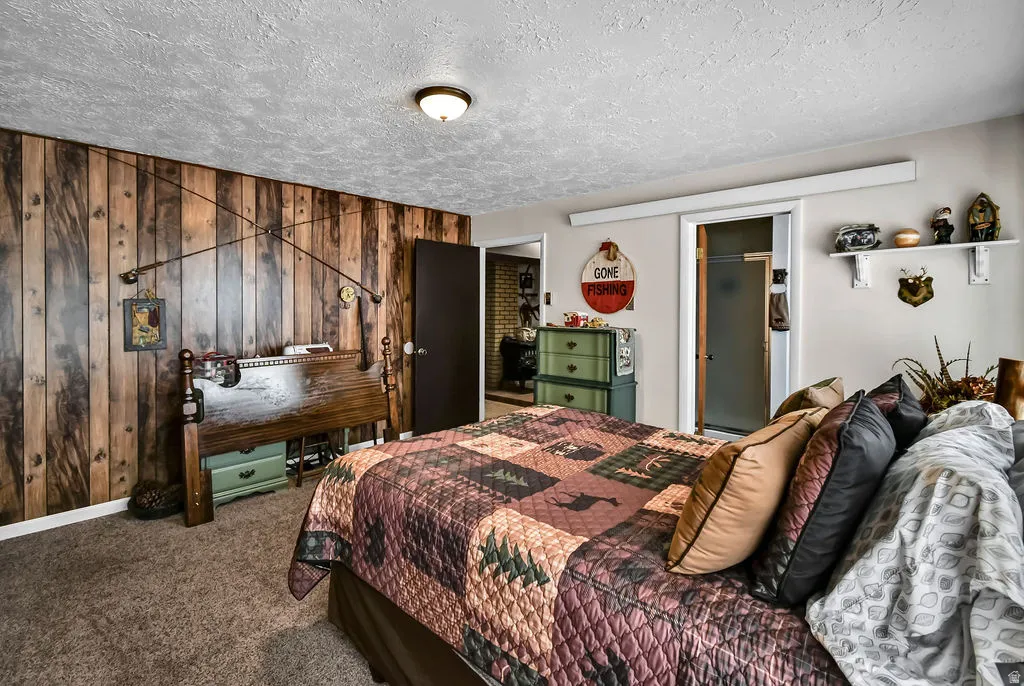 Carpeted bedroom featuring a natural wood-panel accent wall and light gray painted walls