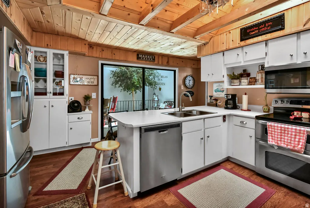 Kitchen featuring wood-finish flooring, white cabinetry, solid surface countertops, and stainless steel appliances