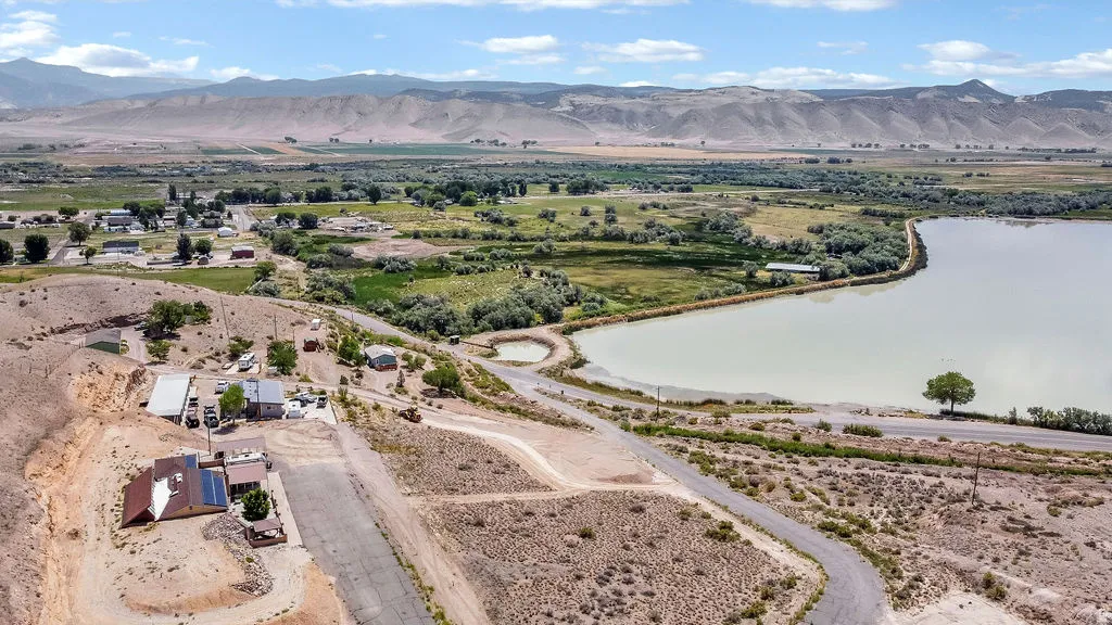 Aerial landscape featuring a body of water, distant mountains, and multiple residential structures