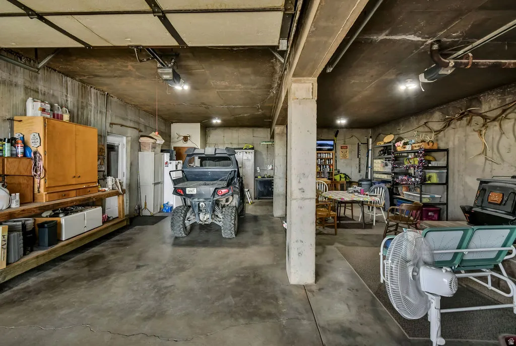 Spacious garage with concrete flooring, exposed ceiling beams, and integrated lighting