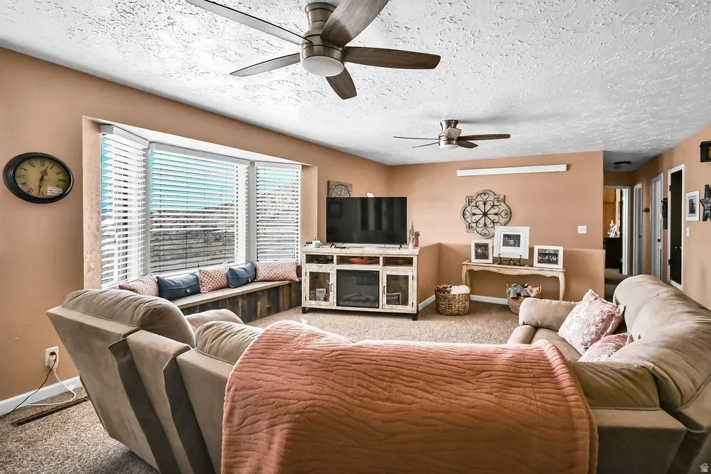 Spacious living area featuring a bay window with a built-in window seat, two ceiling fans, and neutral wall tones