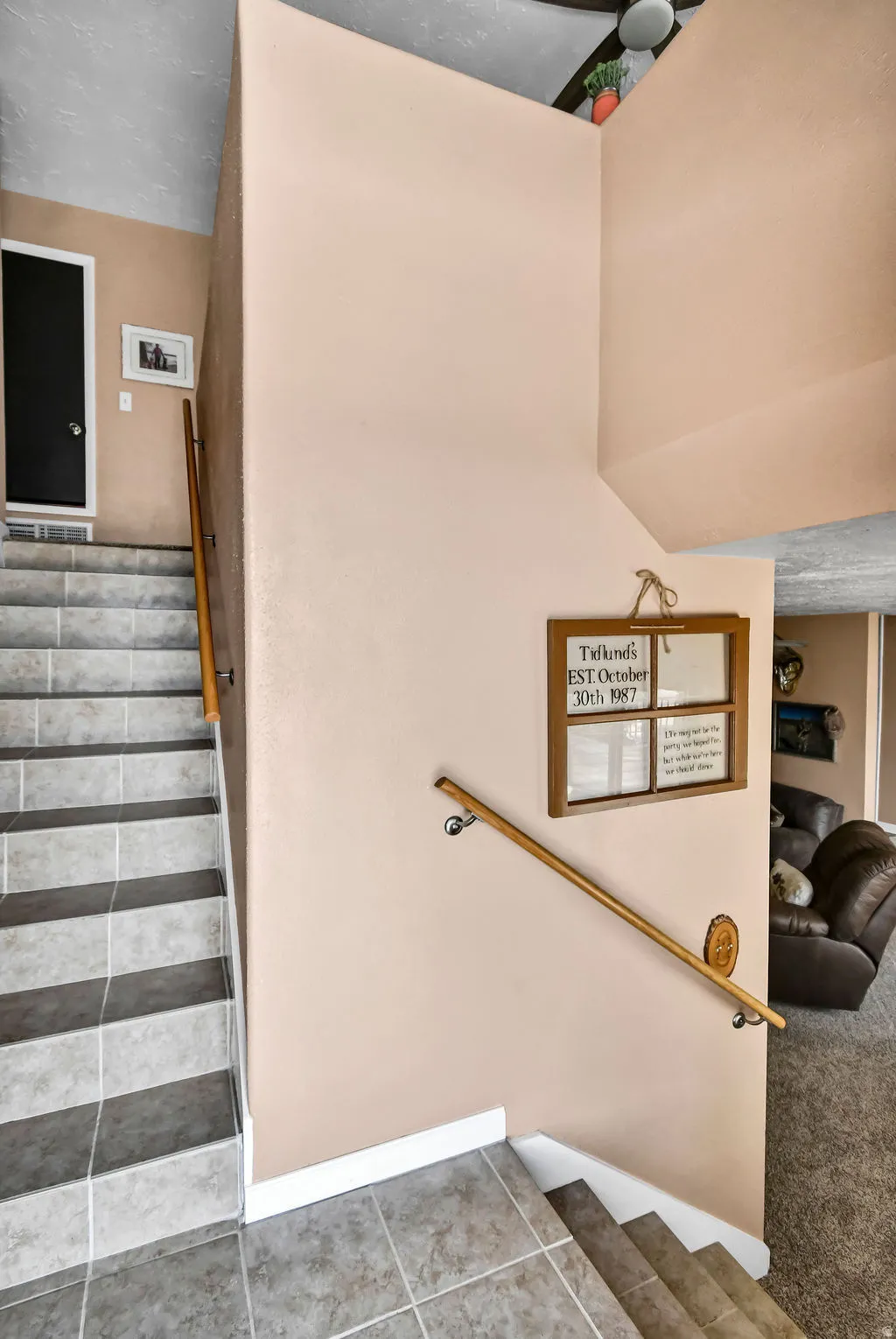 Multi-level staircase featuring neutral-toned tile flooring and a wooden handrail with chrome supports