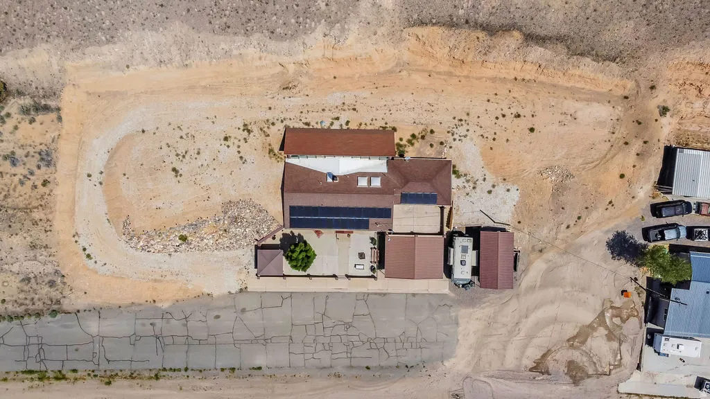 Aerial perspective of a property featuring a single-story residence with a brown shingle roof and solar panels