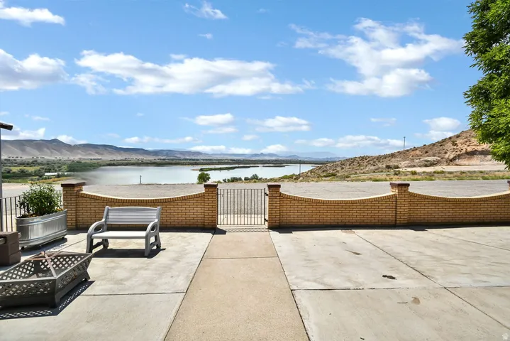 Expansive outdoor patio featuring a concrete surface, a decorative brick wall, and a metal gate