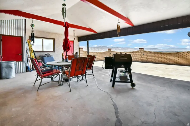 Covered patio with a concrete surface, red-painted structural beams, and a corrugated metal accent wall