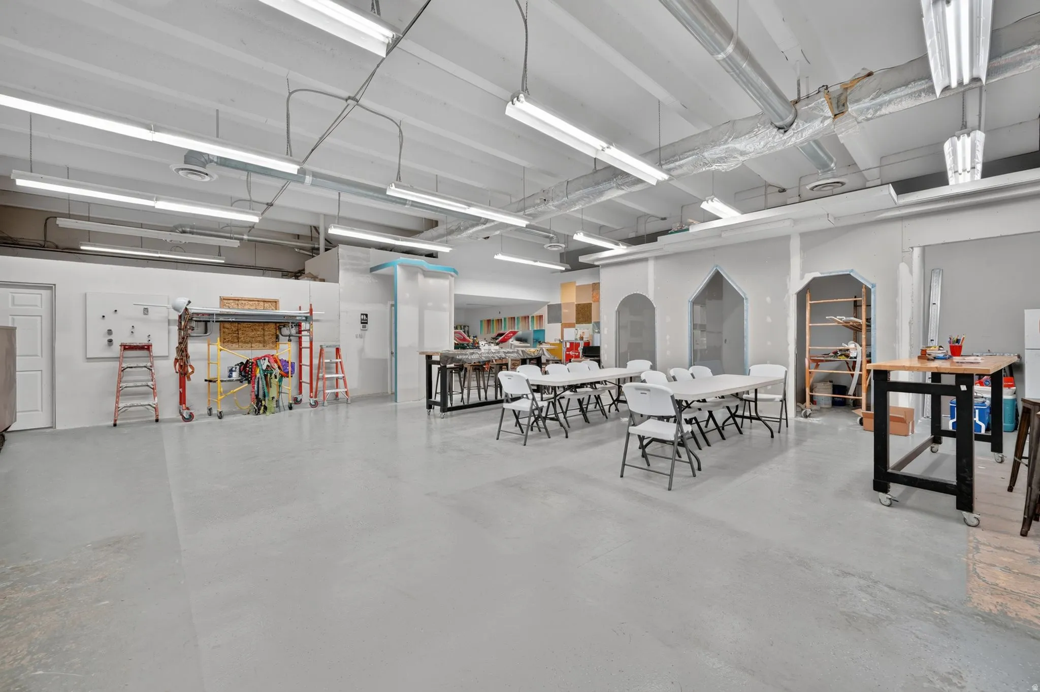 Expansive interior space featuring light gray flooring and exposed overhead ductwork