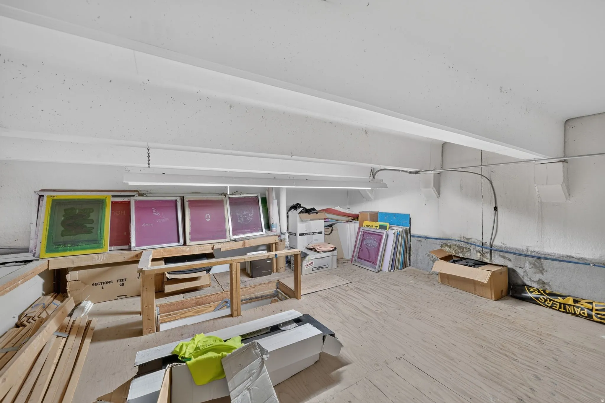Open unfinished space featuring exposed ceiling joists and strip lighting