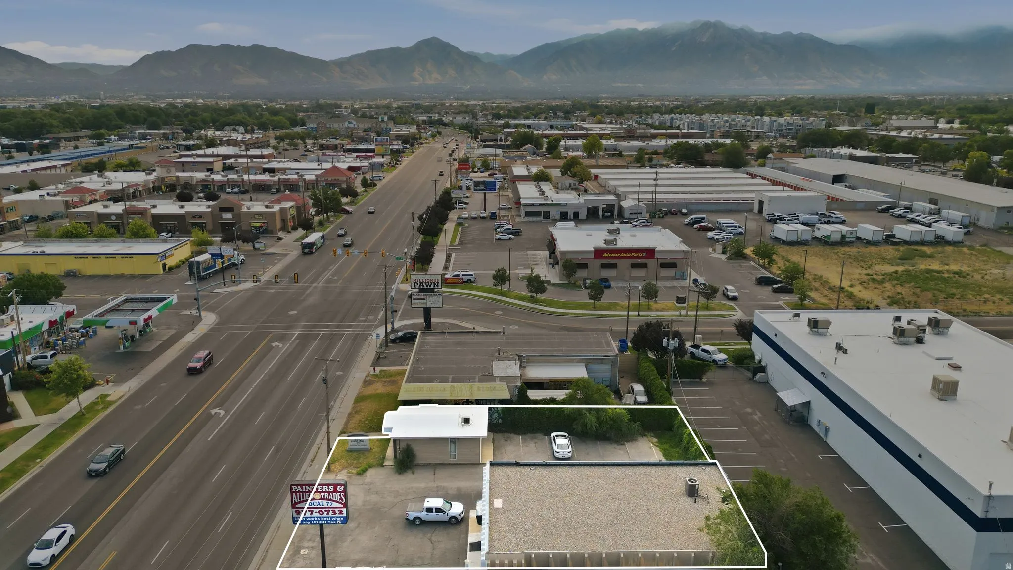 Commercial property featuring a prominent frontage building with a flat roof, an extensive gravel parking area, and a secondary paved parking zone