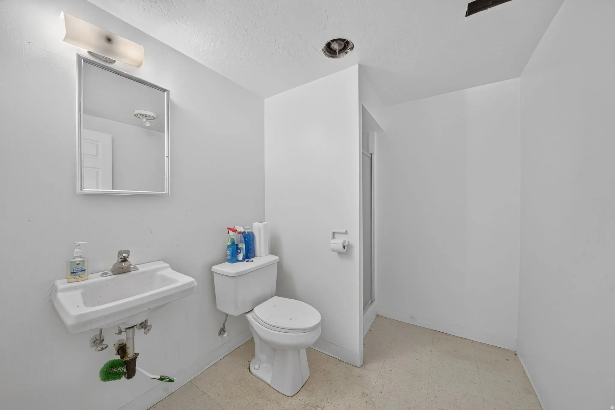 Bathroom featuring a wall-mounted sink, a toilet, and an enclosed shower stall