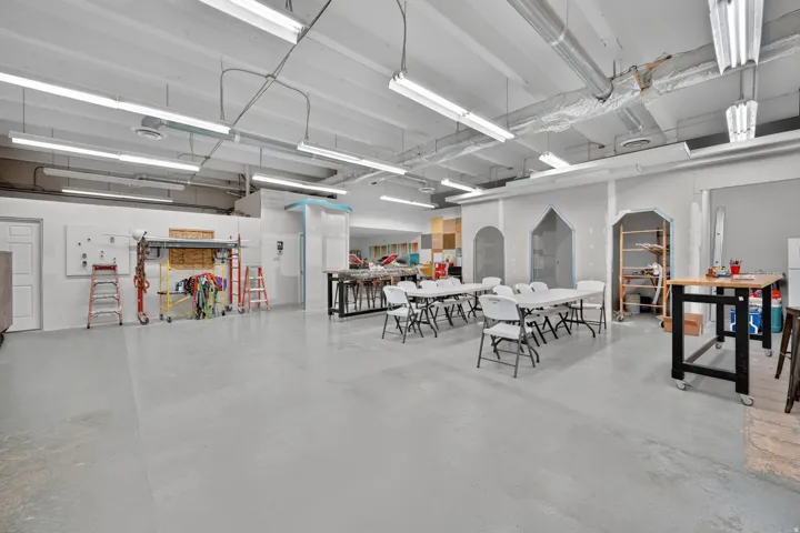 Expansive interior space featuring light gray flooring and exposed overhead ductwork