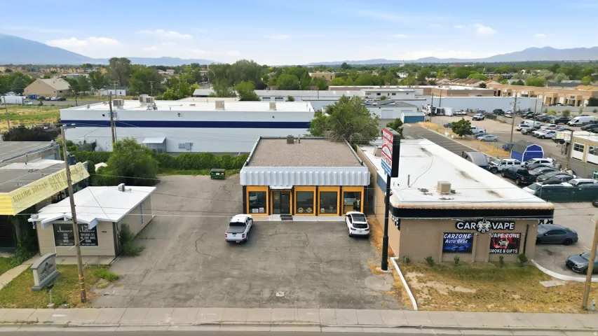 Commercial property featuring a paved parking lot and a single-story building with multiple display windows and an awning