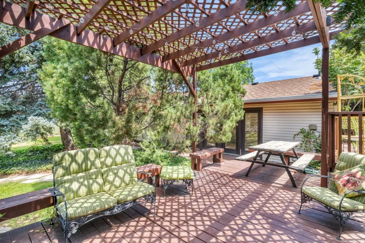 Expansive outdoor deck featuring a wooden pergola, lattice roof, and recessed lighting
