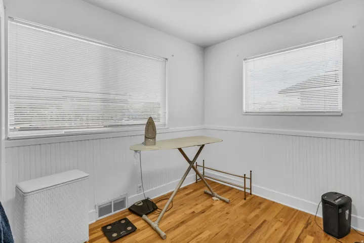 Room featuring wood-finish flooring, white paneled wainscoting, and white walls