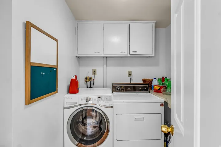 Dedicated utility space featuring overhead white cabinetry for storage, white walls, and a built-in counter surface