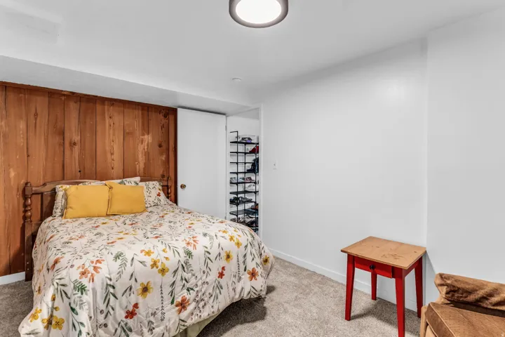 Interior room with wood-paneled accent wall, neutral carpeting, and white painted walls