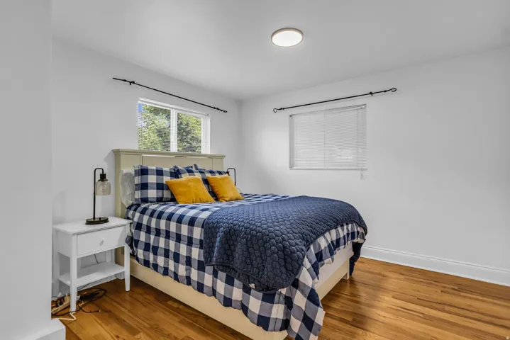 Bright bedroom featuring wood-finish flooring, white walls, and a light-colored bed frame