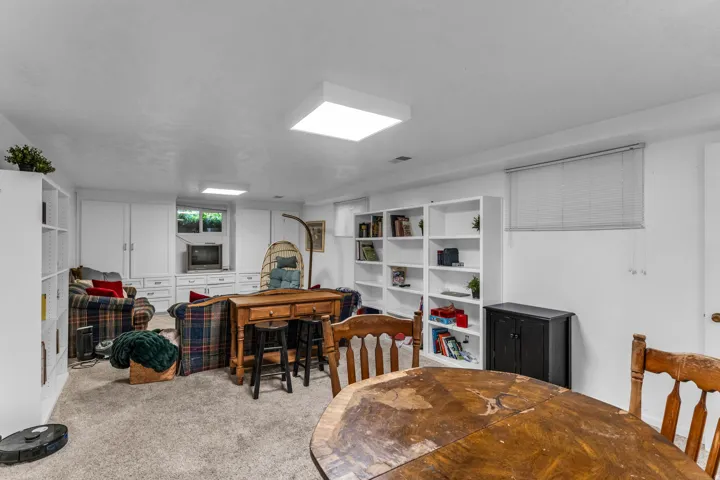 Spacious room featuring light-colored carpeting, multiple built-in shelving units, and integrated cabinetry