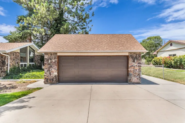 Detached garage with stone veneer accents and a brown panel garage door