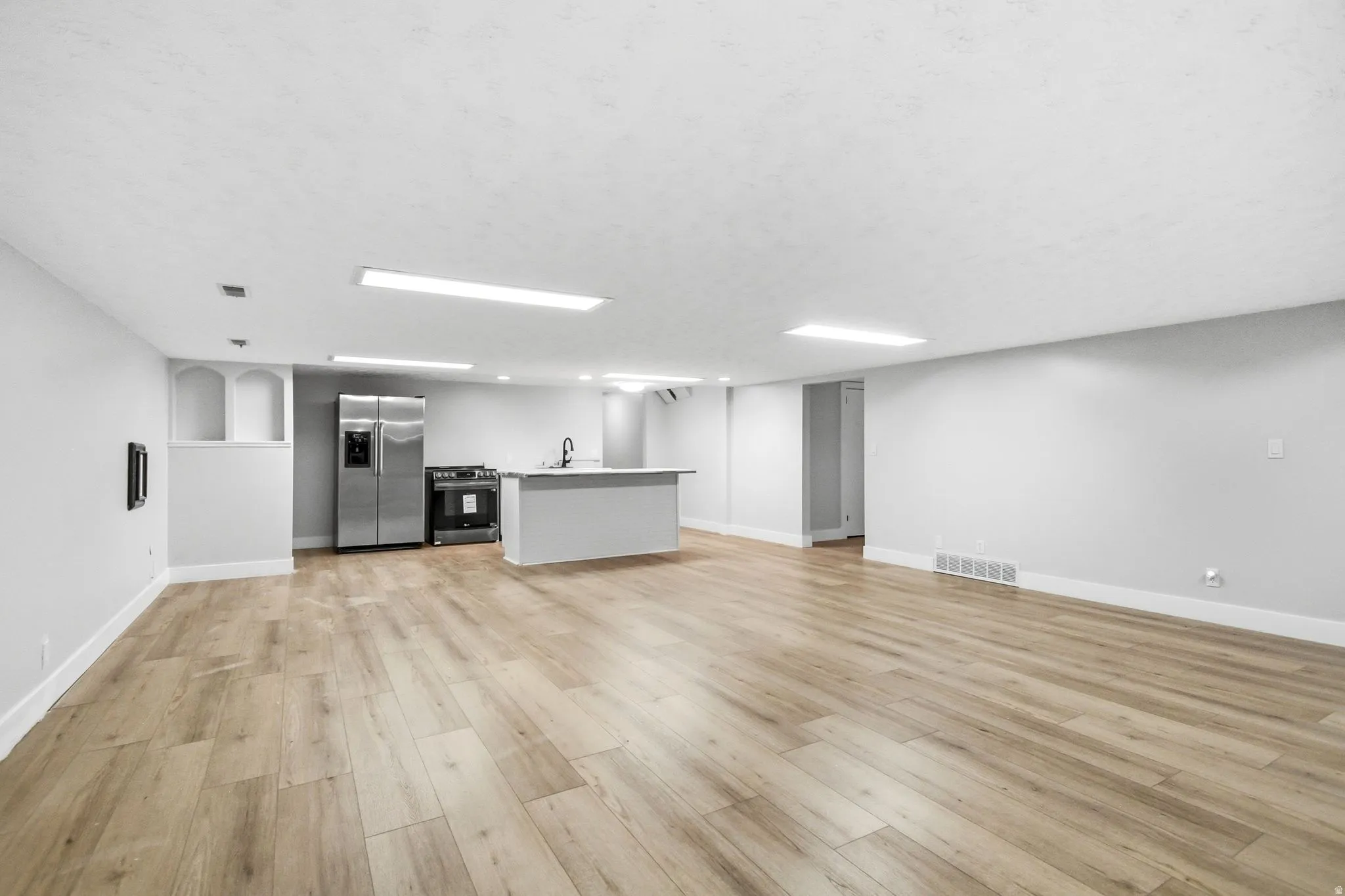 Open-concept living space featuring wood-finish flooring, recessed lighting, and a neutral color palette