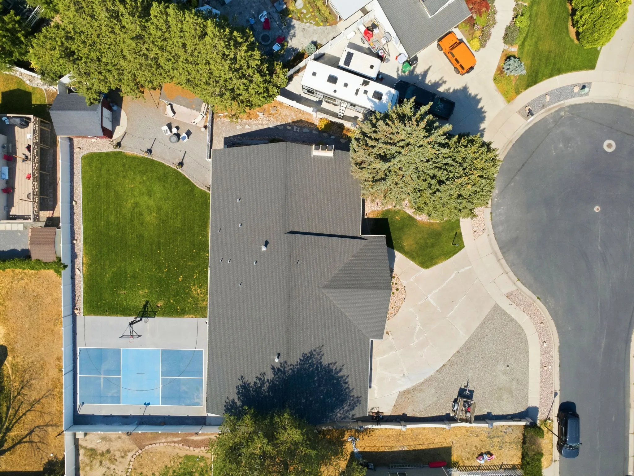 Expansive property featuring a paved driveway, dedicated sports court, and a large manicured lawn