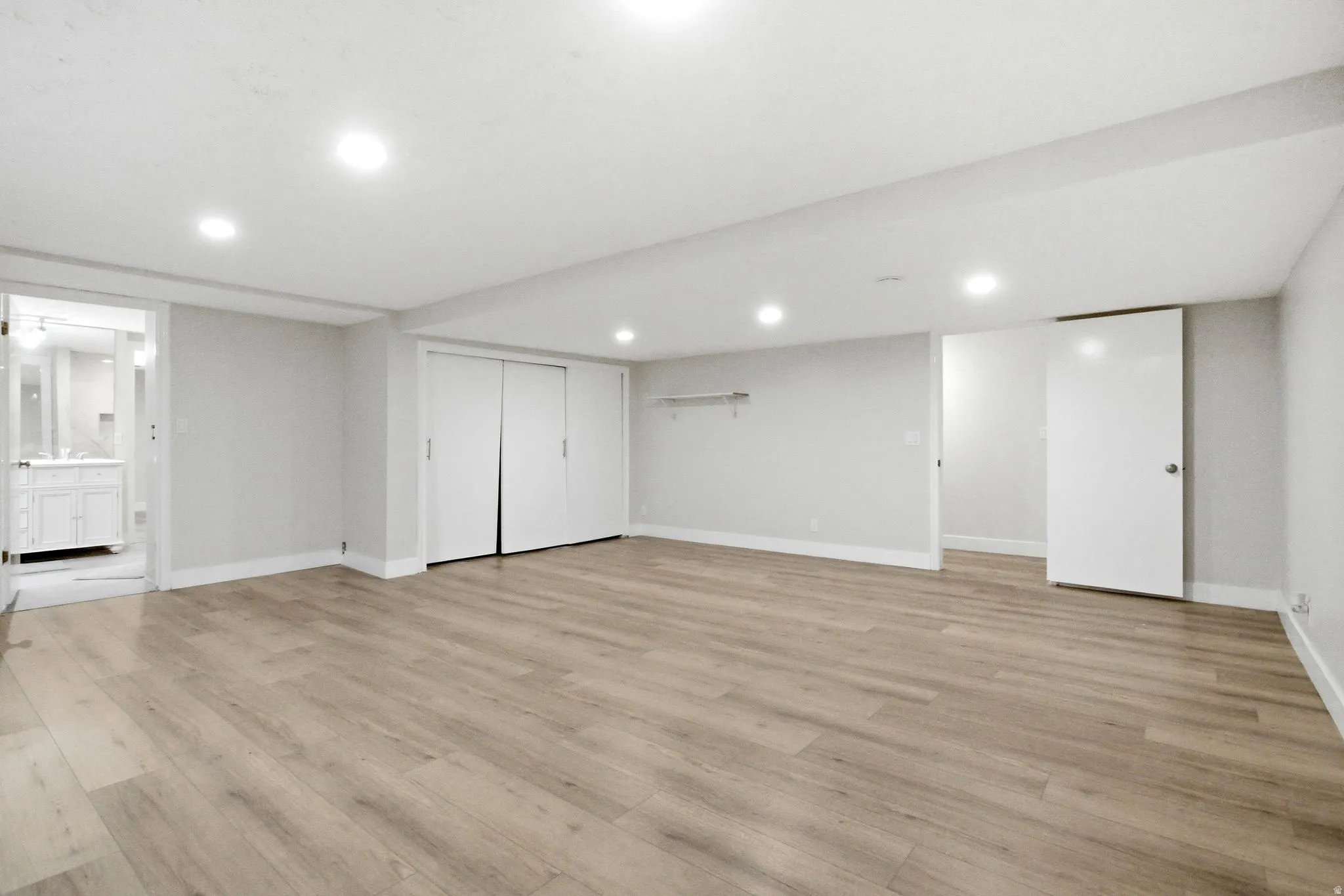 Spacious room featuring wood-finish flooring, recessed lighting, and bright white walls